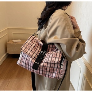 Umhängetasche mit rosa-schwarzem Karomuster und Metallschnalle am Model getragen
