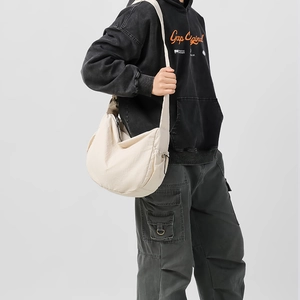 Dettaglio borsa a tracolla a mezzaluna in nylon crema indossata da un modello