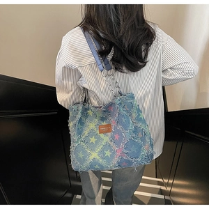 Detail of distressed denim tote bag with colorful stars and metal chain strap