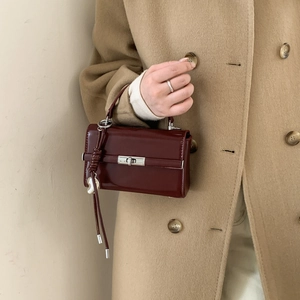 Detail of burgundy PU leather shoulder strap with silver D-ring buckle on a stylish handbag