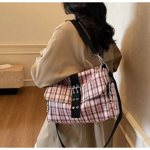 Detail der pink-schwarz karierten Umhängetasche mit Metallschnallen und Nylonriemen