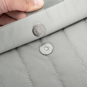 Dettaglio della chiusura magnetica su una borsa porta pc grigia con cuciture verticali