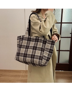Gros plan d'un grand sac cabas à carreaux marron et crème porté à l'épaule