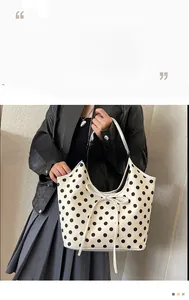 Detail of cream nylon tote bag with large black polka dots and a bow decoration