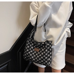 Detail of checkered tote bag featuring distressed fringe edges and metal chain strap
