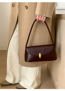 Detail of vintage dark brown leather shoulder bag with a gold oval metal buckle closure