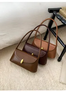 Detailed view of three brown leather shoulder bags with elegant golden oval metal buckles