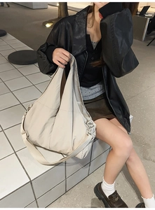 Detailansicht einer großen beigen Tragetasche mit leichter Nylon-Textur an einem Modell