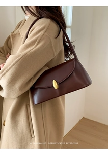 Detail of dark brown leather shoulder bag featuring a sleek gold oval metallic buckle