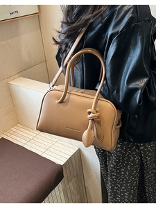 Nahaufnahme der karamellfarbenen Handtasche mit Litschi-Struktur und Fashion & Bags Logo am Model