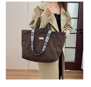 Sac cabas en toile marron avec anses à carreaux porté avec un trench-coat beige