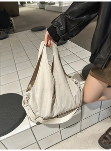 Detail der großen beigen Nylon-Tragetasche mit plissierter Textur und stabilen Griffen
