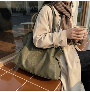 Detail of Malodi embroidered daisy on a large olive green suede tote bag with drawstring