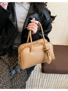 Detailaufnahme der Narbenleder-Textur einer braunen Boston-Tasche mit Prägeschrift