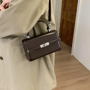 Detail of a structured dark brown lychee leather shoulder bag with metallic lock