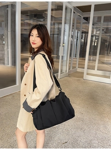 Detail einer schwarzen Falten-Tasche aus Nylon mit breitem Trageriemen am Grabenmantel