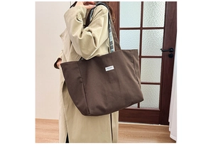 Vue détaillée du grand sac cabas marron porté par un mannequin dans un intérieur chaleureux