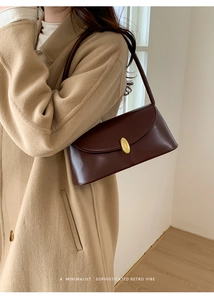 Detailed close-up of retro dark brown leather bag featuring an oval gold buckle closure