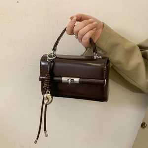 Detail of dark brown faux leather shoulder strap with silver metal swivel D-ring clasp