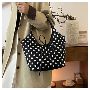 Detail of a vintage black nylon shoulder bag with white polka dots and leather tie strap