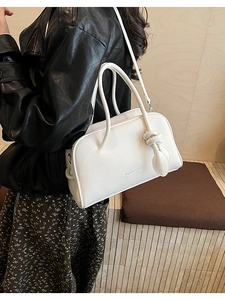 Weiße Boston Bag mit Litchi-Textur und geknotetem Anhänger als Schultertasche getragen