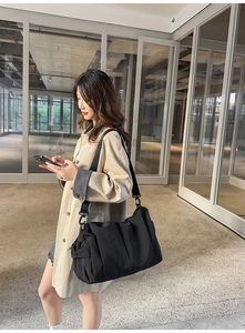 Details einer schwarzen Nylon-Tasche mit Seitentasche und verstellbarem Gurt am Model
