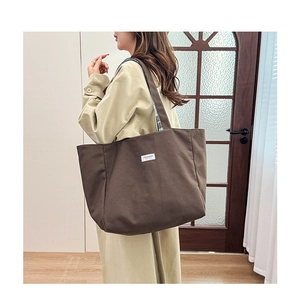 Détail d'un grand sac fourre-tout en toile marron avec étiquette mode à l'épaule