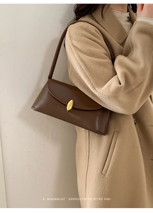 Minimalist dark brown baguette bag with vintage gold buckle shown on a model's shoulder