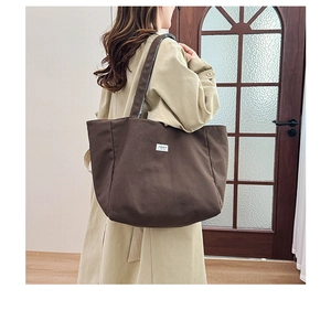 Détail d'un sac cabas à carreaux marron avec étiquette FASHION sur trench beige