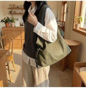 Close-up of olive green tote bag featuring floral embroidery and drawstring closure
