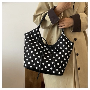 Detail of nylon polka dot tote bag featuring a leather bow and premium polished fabric