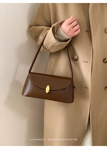 Detail of vintage brown baguette bag with gold buckle on a model's shoulder