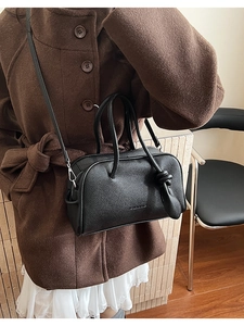 Nahaufnahme der schwarzen Handtasche mit Lychee-Lederstruktur und Schultergurt