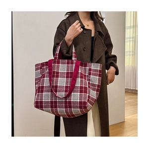 Gros plan d'un grand sac cabas à carreaux rouges avec des sangles porté par un mannequin