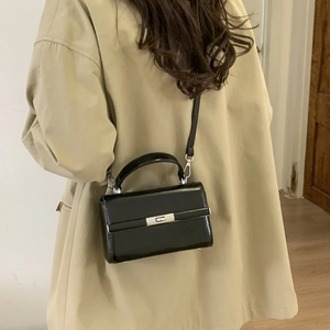 Adjustable black litchi grain PU leather shoulder strap with silver metal buckles on a bag