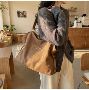 Detail of a brown leather tote bag featuring Maodi lettering and daisy print in a cafe setting