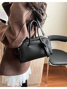 Detail der schwarzen Handtasche aus Leder mit feiner Narbung und geknotetem Doppelgriff