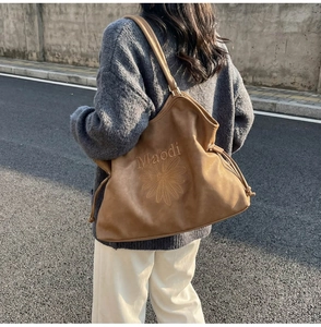 Detail of a brown large tote bag with floral embroidery on a model in street style