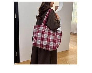 Vue latérale d'un grand sac cabas en laine à carreaux rouge et gris porté par un mannequin