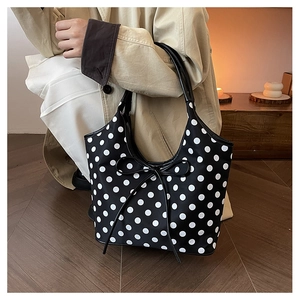 Detail of trendy black nylon tote bag with white polka dots and front bow decoration