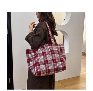 Gros plan du sac cabas à carreaux rouge et blanc porté par un mannequin au style chic