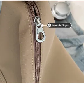 Close-up of smooth silver metal zipper and ripstop nylon texture on khaki shoulder bag