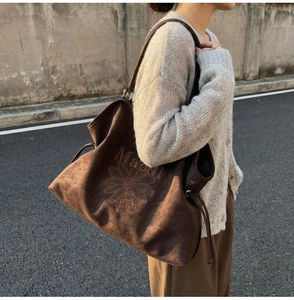 Detail of floral embroidery and drawstring design on a vintage brown suede tote bag