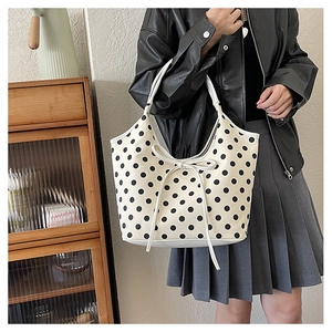 Detail view of large nylon tote bag featuring black polka dots and white bow decoration