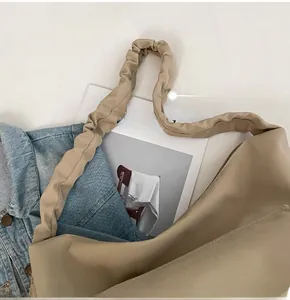 Close-up of khaki nylon tote bag with soft ruffled handle and denim casual styling