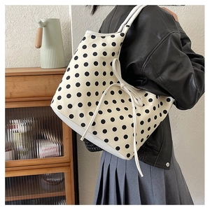 Detail of large nylon tote bag featuring black polka dots and stylish bow drawstring side