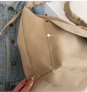 Detailed view of precise stitching on minimalist beige nylon tote bag with props