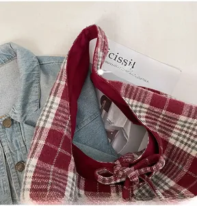 Close-up of red plaid tote bag with bow knot detail and sturdy handles for autumn
