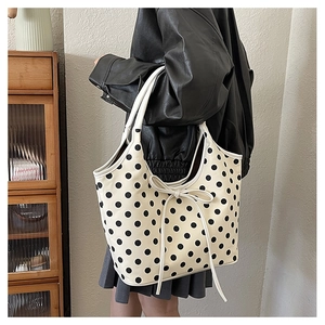 Close-up of a large white tote bag with black polka dots and a slender bow detail