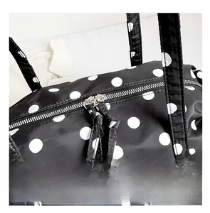 Gros plan du sac de voyage à pois noir et blanc montrant les doubles fermetures éclair
